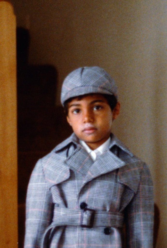 Young boy in plaid cap and trench coat, cinematic styling.